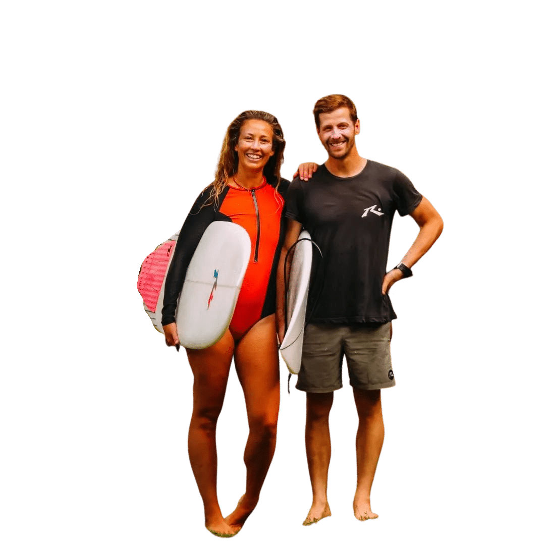 Smiling man and woman standing barefoot holding surfboards, ready for surfing.